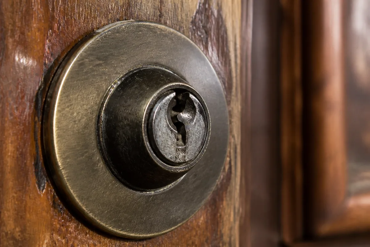 Détail d&rsquo;une entrée de clé de cylindre européen encrassée sur une porte en bois, éclairage frontal