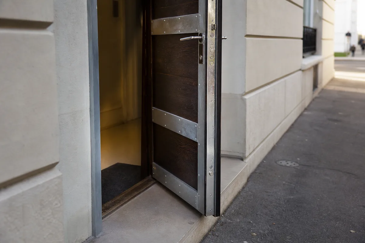 Porte d&rsquo;entrée renforcée avec cornières métalliques visibles, lumière naturelle